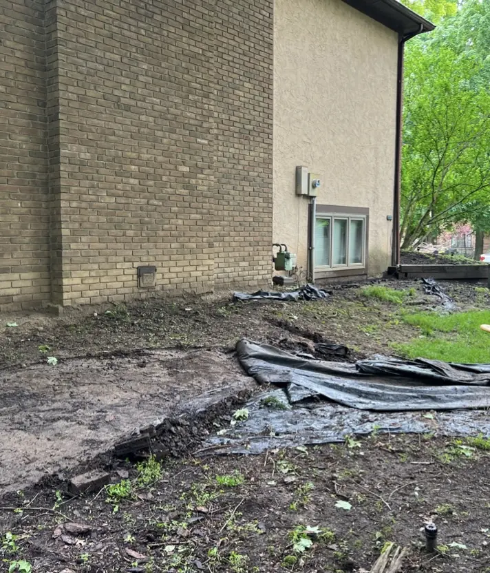 A torn-up muddy corner beside the house before the work started